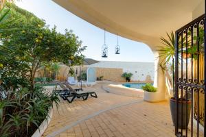a patio with a pool and benches and trees at Villas2go2 V5 Vilamoura XXI in Vilamoura