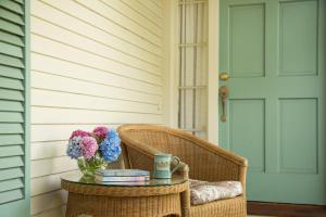 a wicker chair with a table with a vase of flowers at Captain Farris House in South Yarmouth