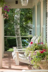 una panchina bianca seduta su un portico con fiori di Captain Farris House a South Yarmouth