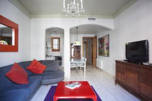 ein Wohnzimmer mit einem blauen Sofa und einem TV in der Unterkunft ApartEasy - Authentic Family Apartment in Barcelona