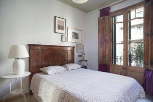 Schlafzimmer mit einem Bett mit einem Kopfteil aus Holz und einem Fenster in der Unterkunft ApartEasy - Authentic Family Apartment in Barcelona