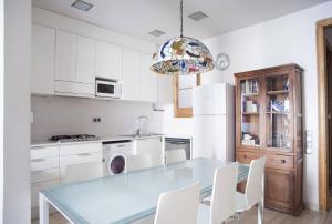 eine Küche mit einem Glastisch und weißen Schränken in der Unterkunft ApartEasy - Authentic Family Apartment in Barcelona