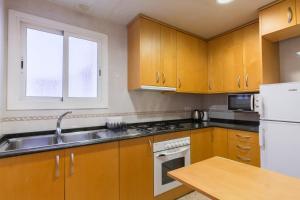 a kitchen with wooden cabinets and a sink at ApartEasy - Port Barcelona in Barcelona