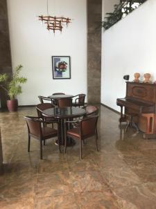 una sala da pranzo con tavolo, sedie e pianoforte di Barra Summer flat a Salvador