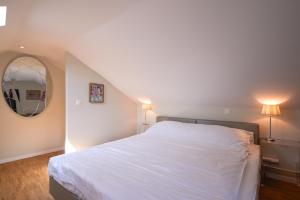 a bedroom with a white bed and a mirror at Aparthotel Hine Adon Fribourg in Fribourg