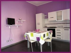サン・ヴィート・ロ・カーポにあるNuovissima casa Vacanze a San Vito Lo Capoの紫の壁のキッチン(テーブル、椅子付)