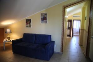 a living room with a blue couch and a hallway at La Luce del Sole in Belpasso