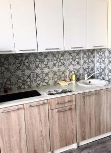 una cocina con armarios blancos y fregadero en ATLANT Apartments 171 en Voronezh