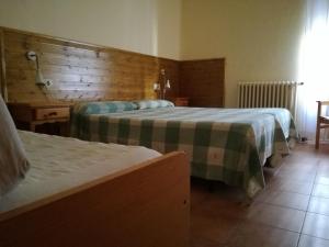 a hotel room with two beds and a wooden wall at Hostal La Catalana in Sant Llorenc de Morunys