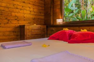 Schlafzimmer mit einem Bett mit roten Kissen und einem Fenster in der Unterkunft Le matelot de la baie in Deshaies