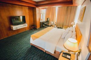 um quarto de hotel com uma cama grande e uma televisão em Butuan Grand Palace Hotel em Butuan