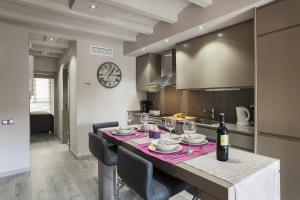 バルセロナにあるElegant Eixample Apartment nicely decoratedのキッチン(ワイングラスと時計付きのテーブル付)