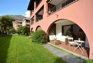 een roze gebouw met een patio met een tafel en stoelen bij Sabrina 09 in Ascona