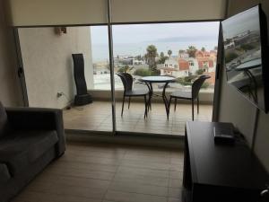 a living room with a table and chairs on a balcony at Apartamento en Club Oceano in Coquimbo