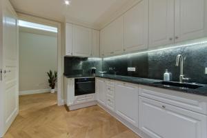 a kitchen with white cabinets and a sink at Apartament Molo Superior in Sopot