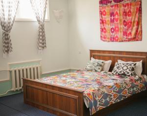 1 dormitorio con 1 cama con colcha colorida en Guest House Ikathouse en Margilan
