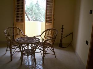 three chairs and a table in a room with a window at Arabesque House Apartment in Luxor