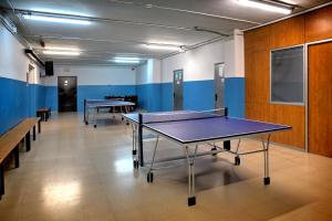 Habitación con 2 mesas de ping pong y bancos en Albergue Era Garona en Salardú