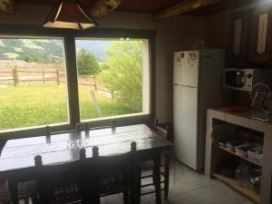 a kitchen with a table and a refrigerator and a window at Albergue Aylen-Aike in El Chalten