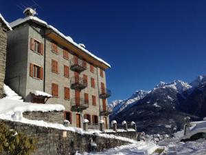 un edificio nella neve con montagne sullo sfondo di B&B Il Paradiso Mozzio a Mozzio