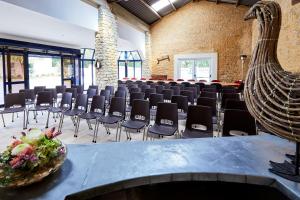 a large room with chairs and a table with a bowl of flowers at Domaine de L'Hostreiere in Colleville-sur-Mer
