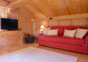 un soggiorno con un divano rosso e una TV di Hotel Roseg-Gletscher a Pontresina