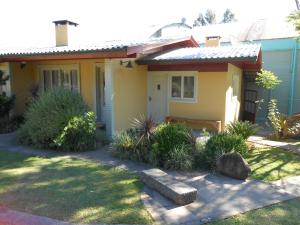 una pequeña casa amarilla con un banco en el patio en Casa para 5 pessoas em Canela - Caracol, en Canela