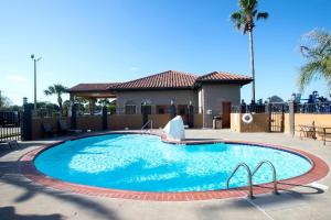 a swimming pool at a resort with a house and palm trees at Best Western Executive Inn El Campo in El Campo
