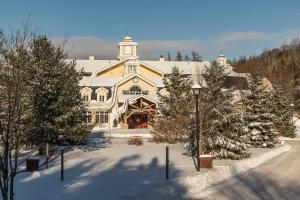 a large house in the snow with snow covered trees at Château Beauvallon in Mont-Tremblant