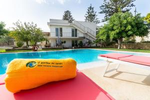 a yellow towel sitting on a bench next to a swimming pool at Il Giardino Dei Carrubi in Donnalucata
