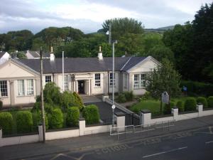 a white house with a fence in front of it at An Caislean Guest House in Ballycastle