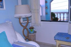 a lamp in a living room with a chair and a window at Dimitra's Sea-Crafts Boutique Studios in Kalyves