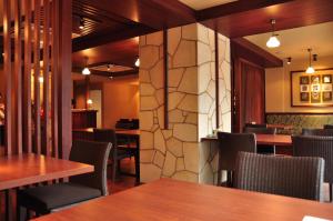 un restaurant avec des tables et des chaises en bois et un mur en pierre dans l'établissement こんぴら温泉 貸切湯の宿 ことね, à Kotohira