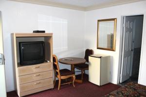 ein Hotelzimmer mit einem TV, einem Tisch und einem kleinen Tisch in der Unterkunft Beacon Motel in Long Beach