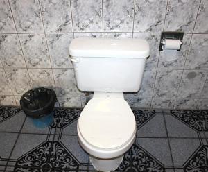 a bathroom with a white toilet and a trash can at Beacon Motel in Long Beach