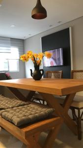 uma mesa de madeira com um vaso com flores em Apartamento Zapata Guarujá no Guarujá