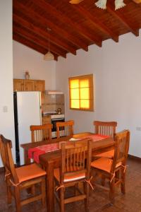 eine Küche mit einem Holztisch mit Stühlen und einem Kühlschrank in der Unterkunft Aguas Mornas Cabañas in Mina Clavero