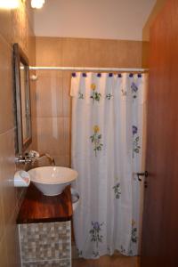 a bathroom with a shower curtain with a sink at Aguas Mornas Cabañas in Mina Clavero
