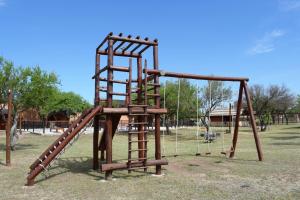 un parque infantil con columpios de madera en Complejo Sol Serrano en Mina Clavero