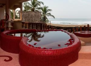 a red bath tub with red flowers in front of a beach at Hotel Villas Punta Blanca in Zihuatanejo