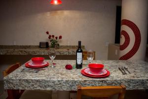 een tafel met rode borden en een fles wijn bij Hotel Villas Punta Blanca in Zihuatanejo