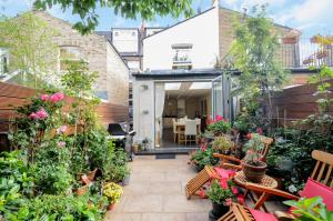 an outdoor patio with a bunch of plants and benches at Georgiana's Guesthouse in London
