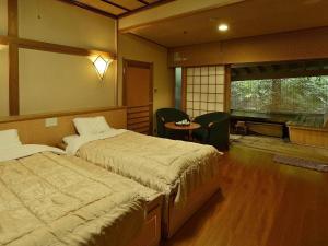 1 Schlafzimmer mit 2 Betten, einem Tisch und Stühlen in der Unterkunft Itoen Hotel Matsukawakan in Ito