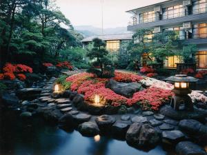 un jardín con flores y luces frente a un edificio en Itoen Hotel Matsukawakan en Ito