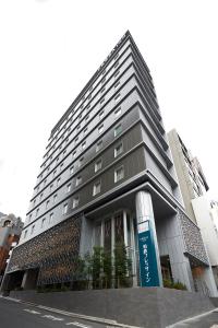 un edificio alto con una señal azul delante de él en Sotetsu Fresa Inn Tokyo Roppongi, en Tokio