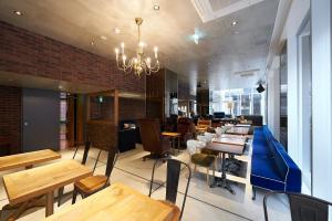 a restaurant with wooden tables and chairs and a chandelier at Sotetsu Fresa Inn Tokyo Roppongi in Tokyo