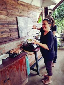 una mujer preparando un plato de comida en una parrilla en Kingfisher House en Sangkhla Buri