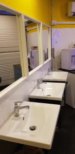 three sinks in a bathroom with two mirrors at Galaxy Pods @ Chinatown in Singapore