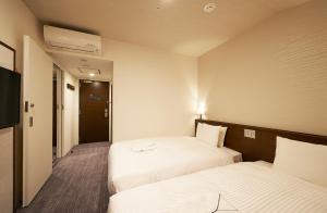 a hotel room with two beds and a television at Sotetsu Fresa Inn Tokyo Roppongi in Tokyo