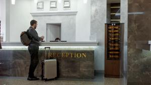 a man standing at a counter with his luggage at Hotel Central (Vostok) in Birobidzhan